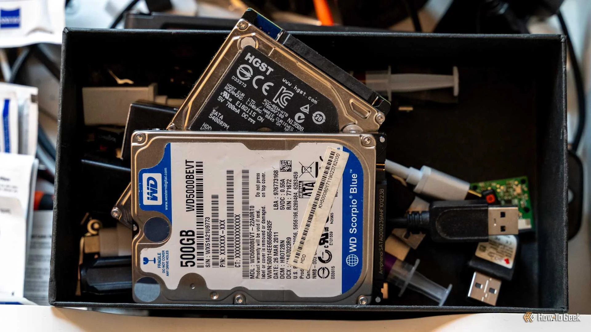A WD Blue and HGST hard drive sitting in an old tech drawer.