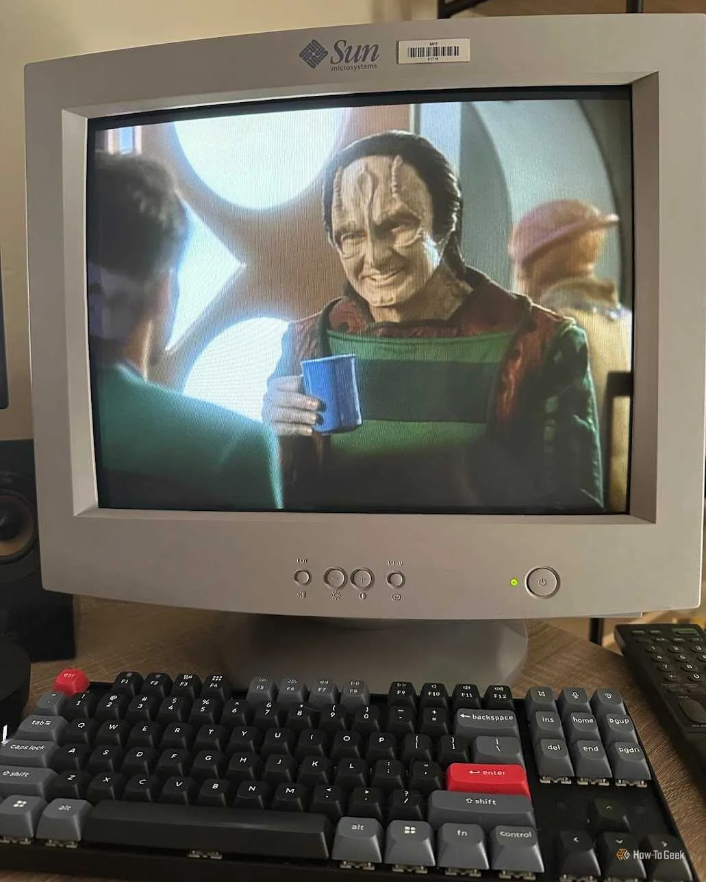 A mechanical keyboard in front of a CRT monitor with a Star Trek TV show playing.