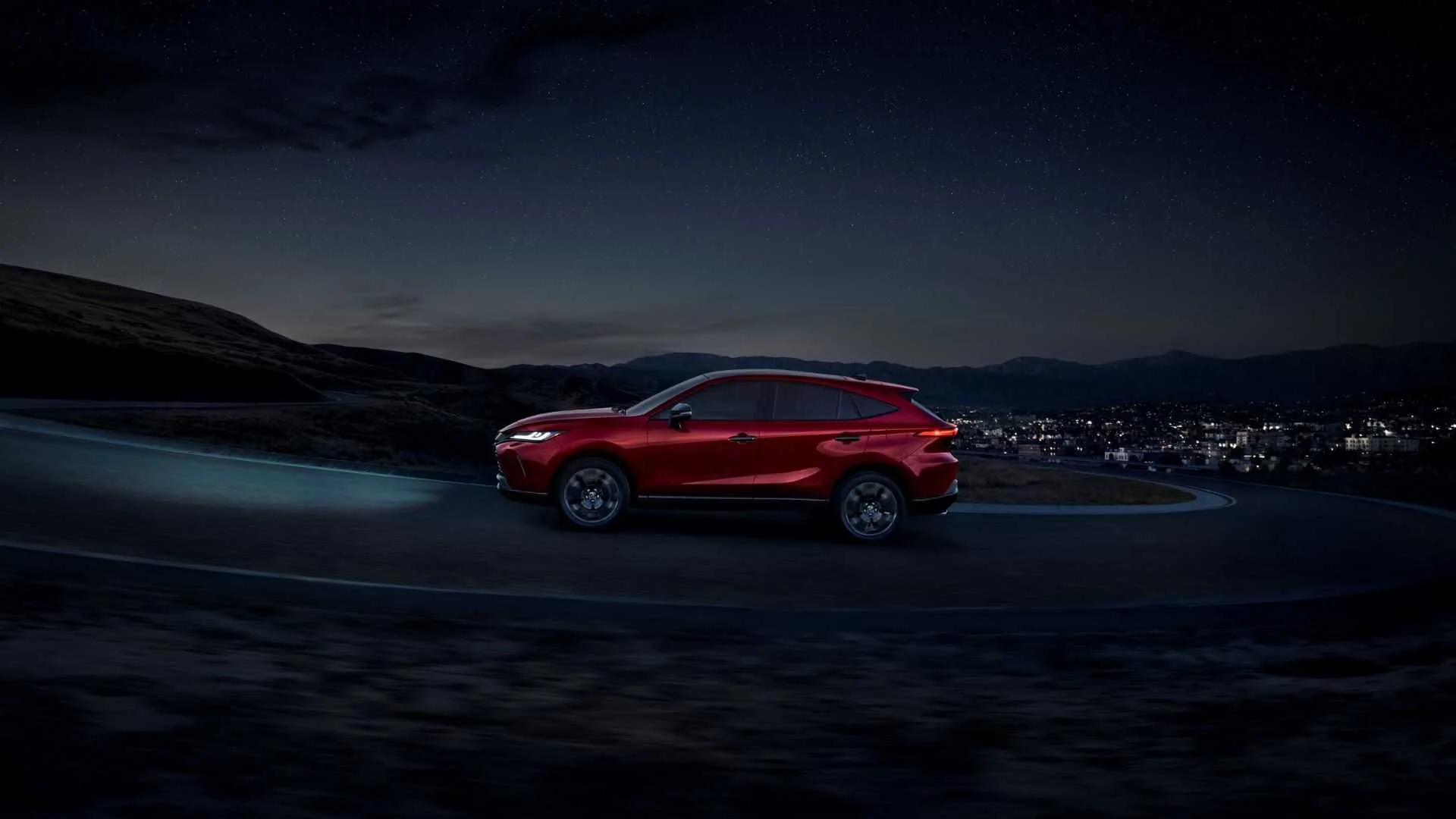 Dynamic side profile shot of a red 2024 Toyota Venza Nightshade.