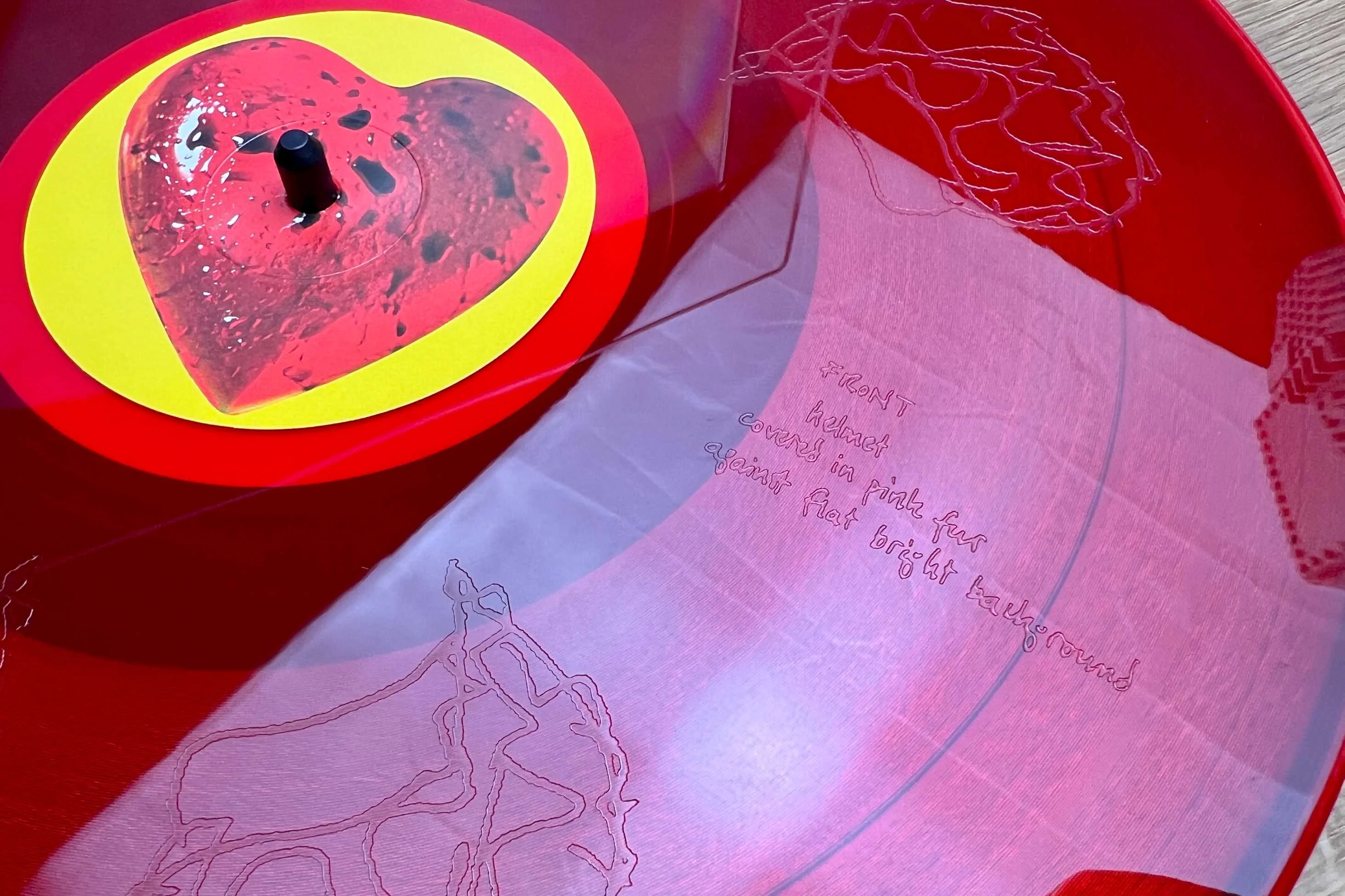A close-up of a red Breeders vinyl records with etchings in it