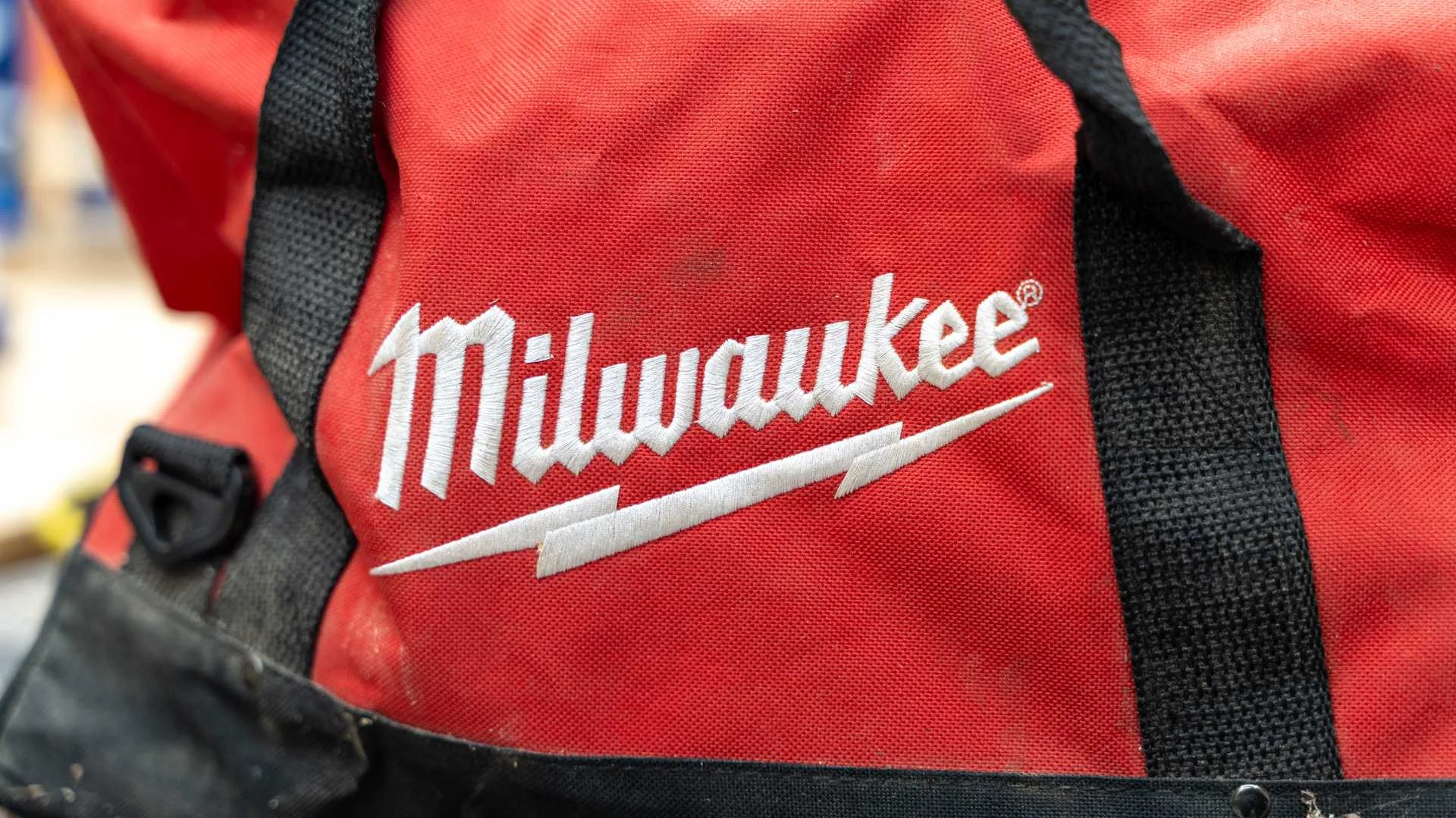 The Milwaukee logo embroidered in white on a red tool bag.