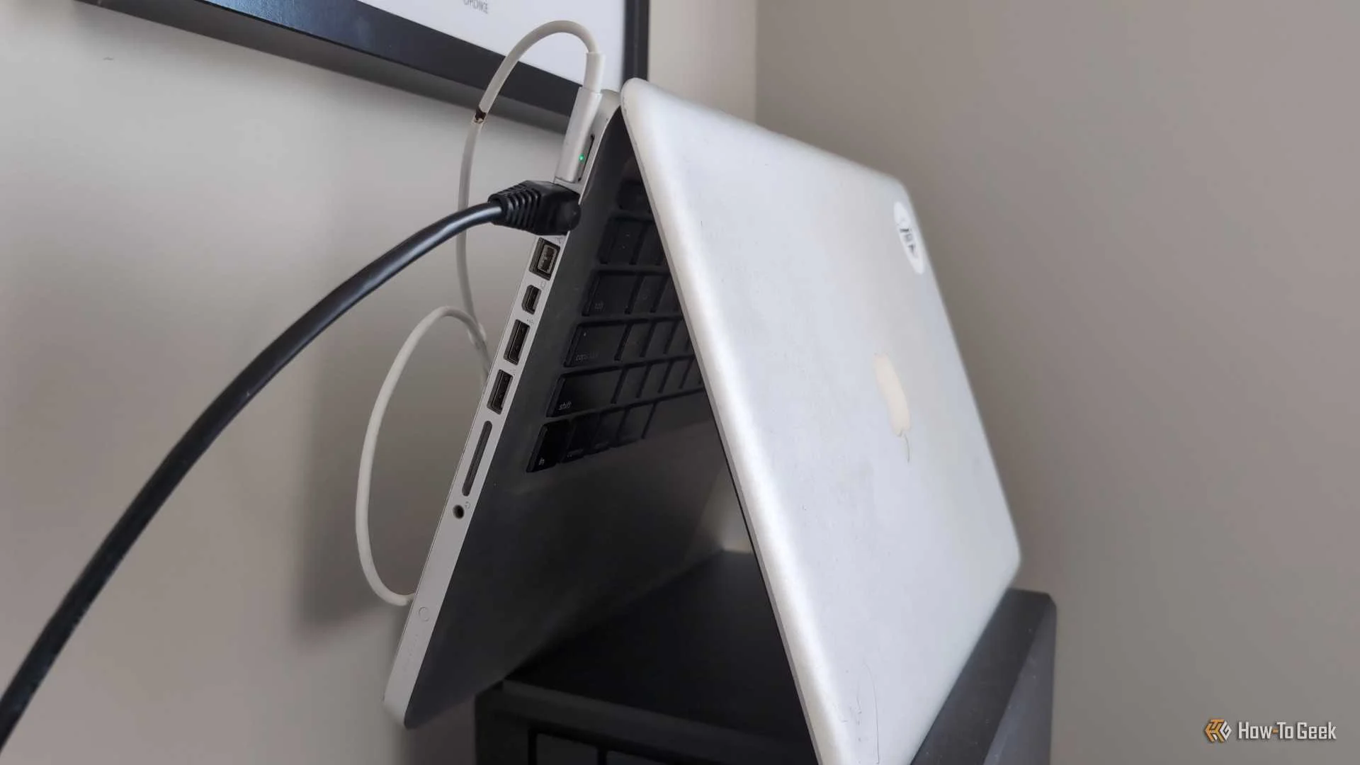An old MacBook laptop stood in the tent position with an Ethernet cable plugged into it.