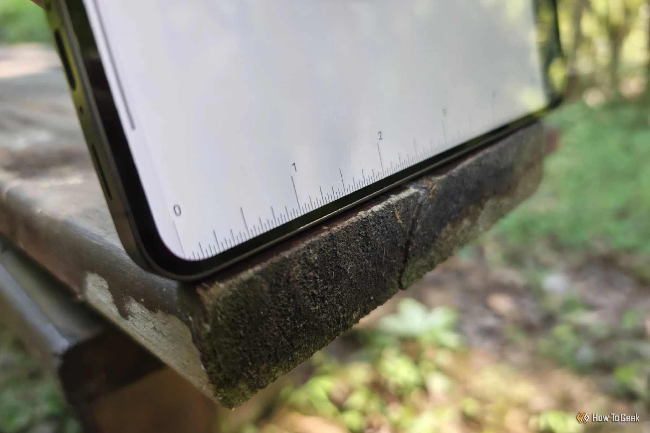 A ruler app displayed on a Samsung Galaxy phone to measure a wooden bench.