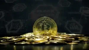 A pile of gold-colored Bitcoin coins with a digital blockchain graphic in the background