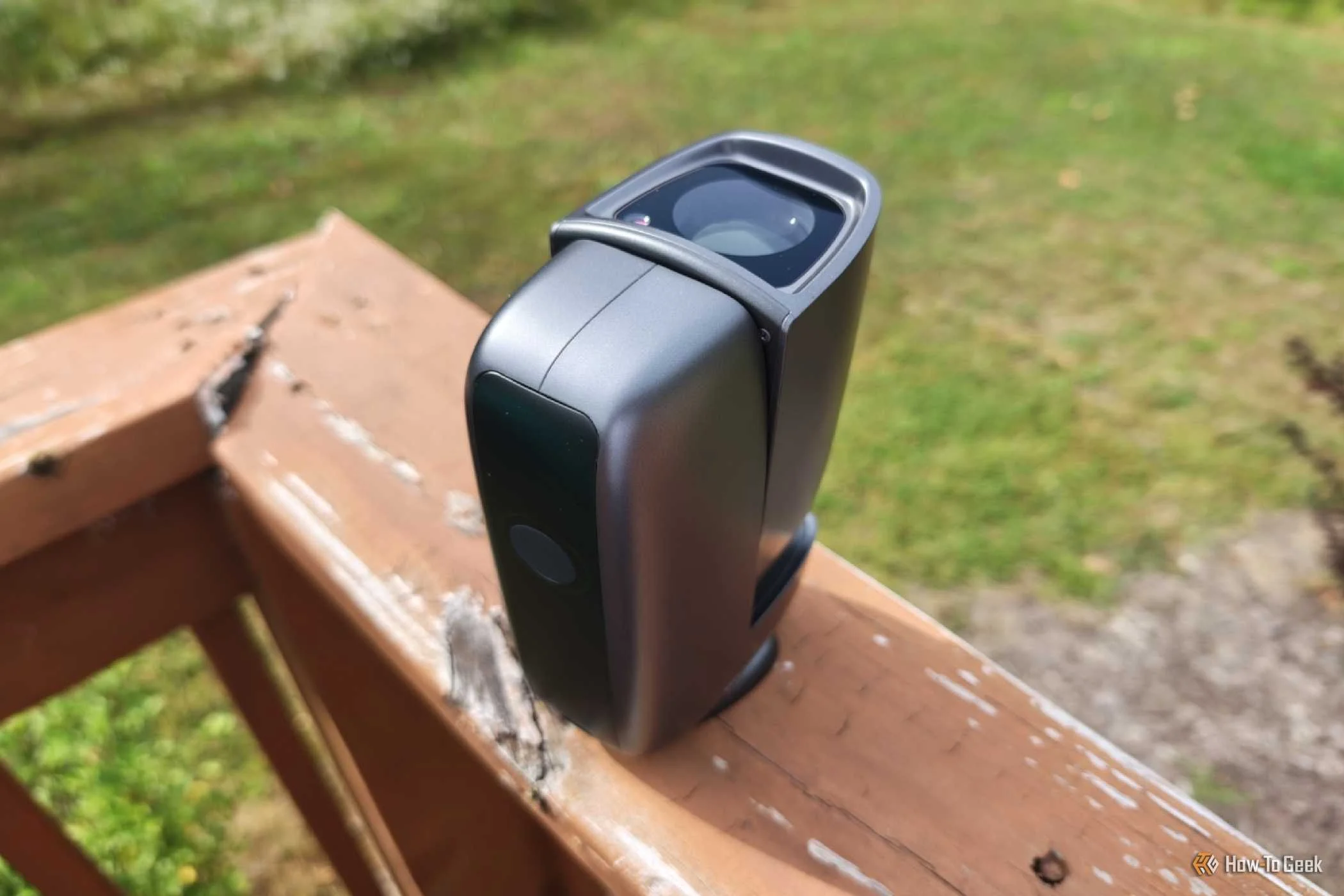 DWARF mini smart telescope on a wooden porch railing with telescope upright.