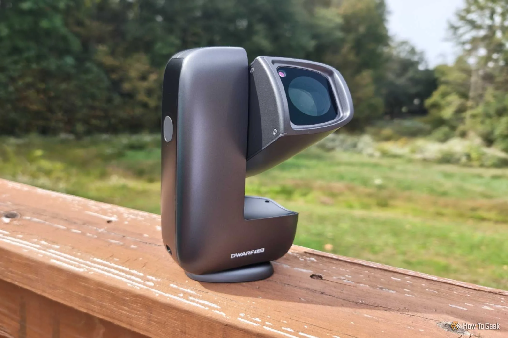 DWARF mini smart telescope on a wooden porch railing with telescope at an angle.