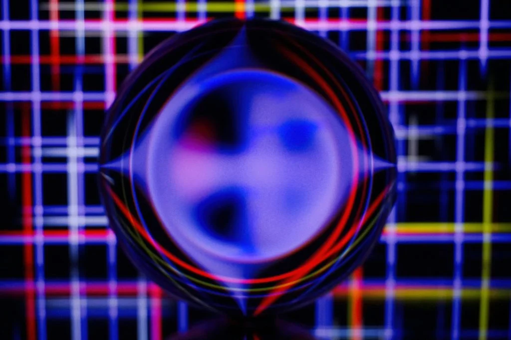 A glass sphere bends a glowing blue, red, and yellow grid of light lines into a blurred circle, suggesting AI agent observability.