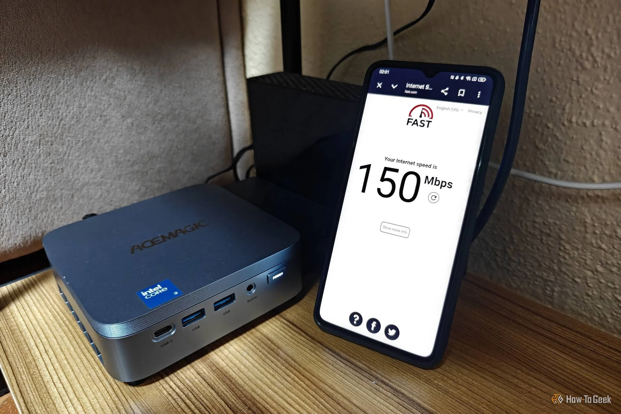 A phone displaying a speed test next to a mini PC that runs as a home server.