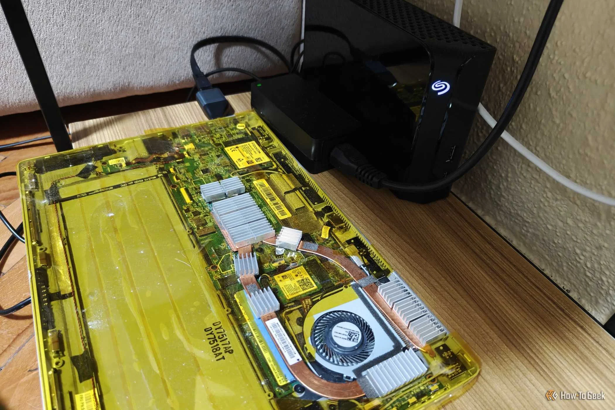 A laptop that's being used as a home server with an external hard drive next to it and an Ethernet adapter plugged in.